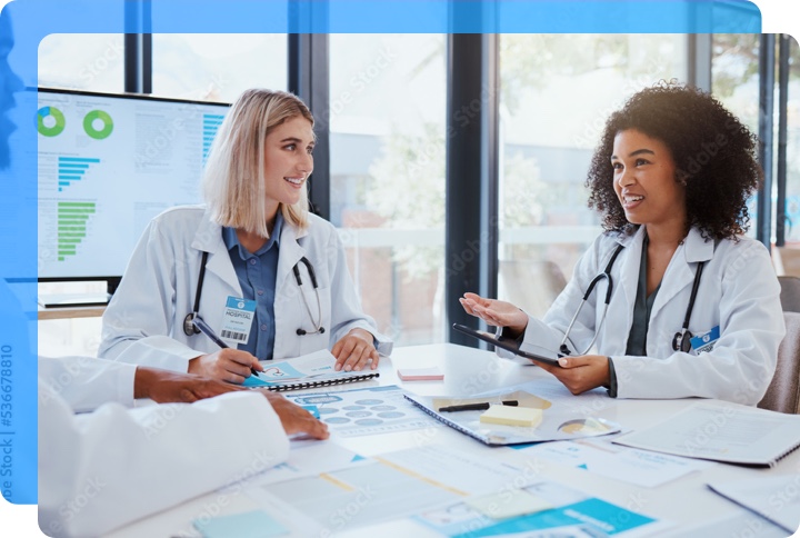 Two woman nurses discussing ideas with charts and data to work to find the best solution
